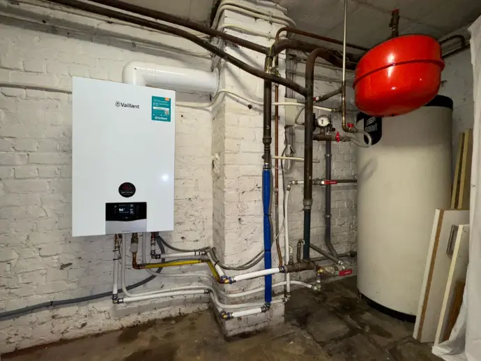 Installation professionnelle d’une chaudière à gaz à condensation avec boiler intégré, optimisée pour le chauffage domestique et la production d’eau chaude sanitaire. L’équipement est installé avec des finitions soignées, présentant les raccordements de gaz, d’eau et d’électricité conformes aux normes en vigueur. Idéal pour illustrer la performance énergétique, la fiabilité et l’efficacité d’un système de chauffage moderne, adapté aux maisons et appartements. Cette image met en avant un espace technique clair et bien organisé, reflétant la qualité d’une installation certifiée et durable.
